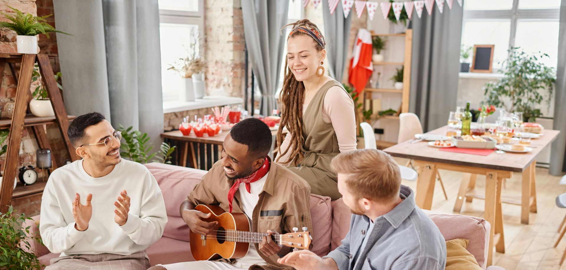 Group of friends enjoying music and conversation indoors, sharing a joyful moment together.